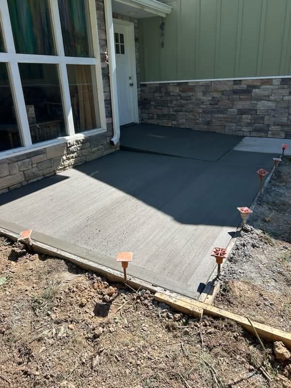 Finished concrete walkway at the front entry of a stone-veneer home